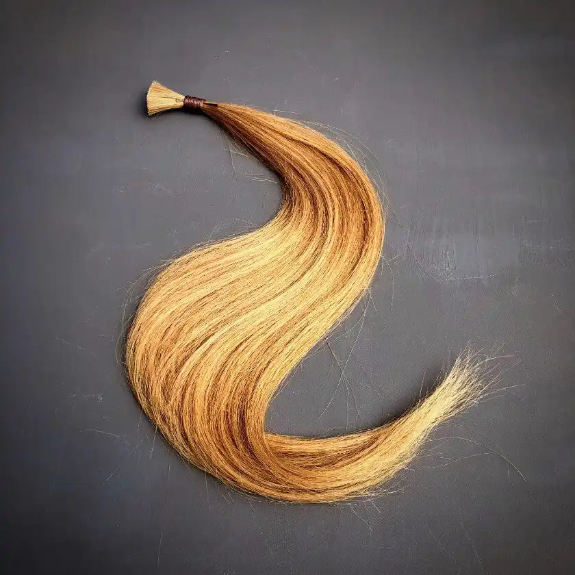 Ein Bündel langer, lockiger, blonder Haare mit dunkleren Ansätzen.