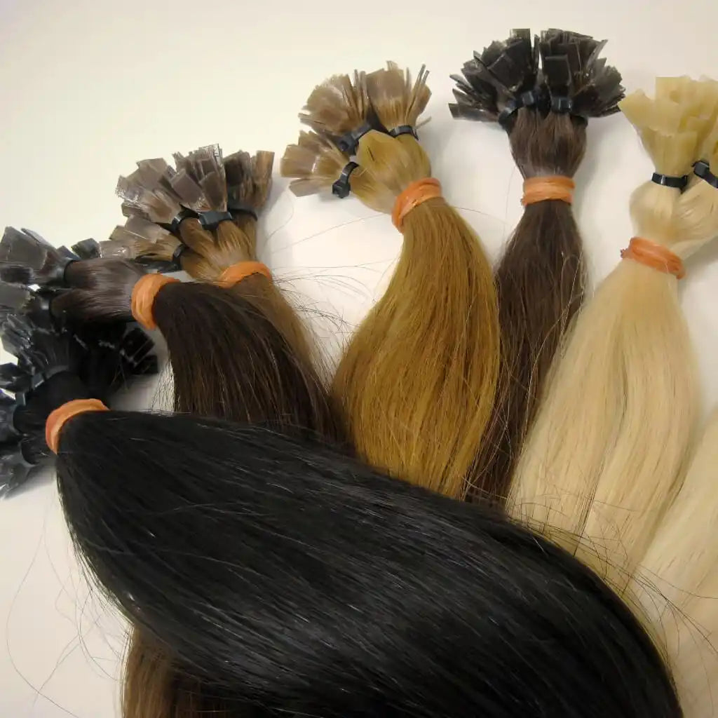 Pakete von menschlichen Haarverlängerungen in verschiedenen Farben, von Schwarz bis Blond, mit Keratinfusionsspitzen.