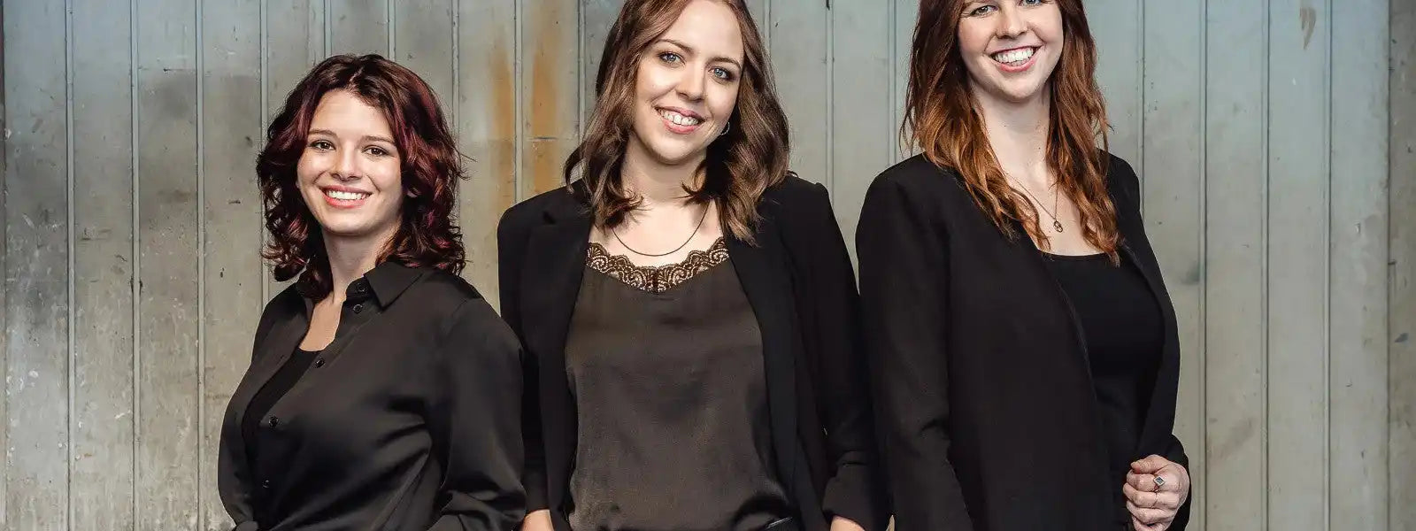 Drei lächelnde Frauen, die für ein professionelles Porträt posieren.