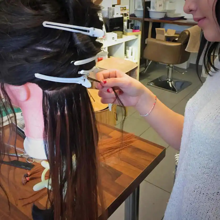 Eine Schaufensterpuppe mit langen, dunklen Extensions im Haar, die aufgesetzt werden.